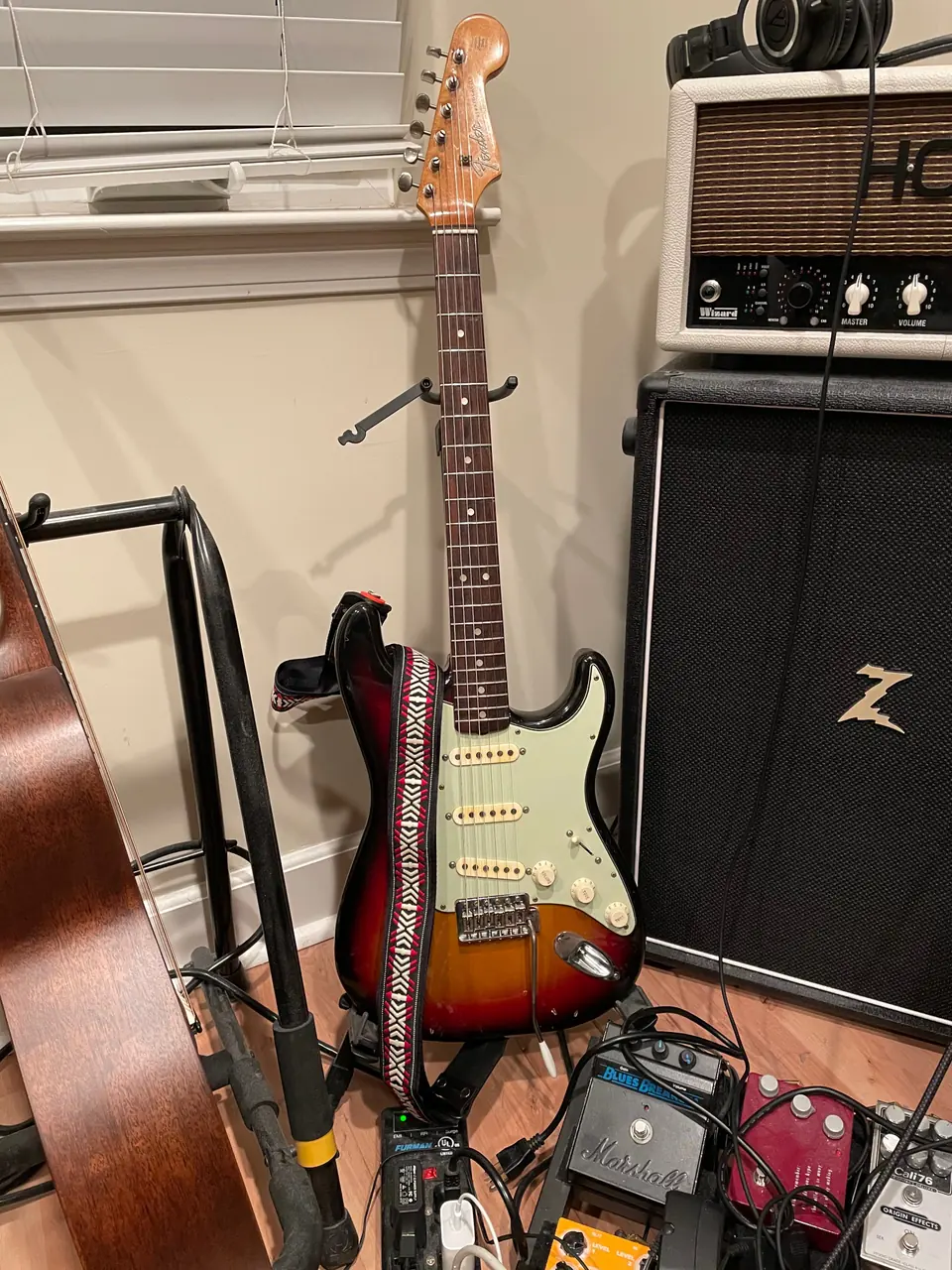 Partscaster Stratocaster on a stand, surrounded by amps and pedals